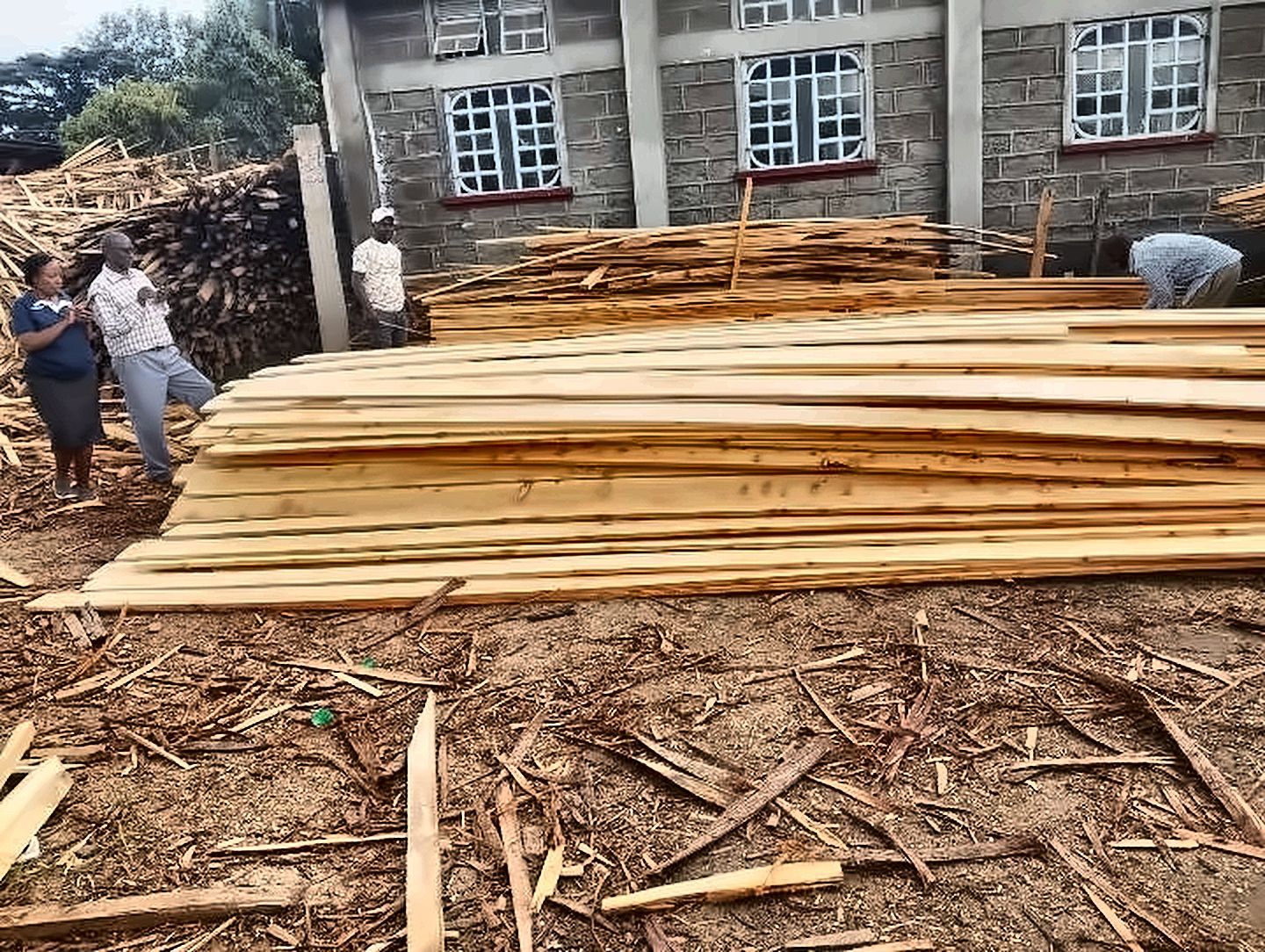 Long stacks of freshly sawn timber boards in the yard with customers looking on