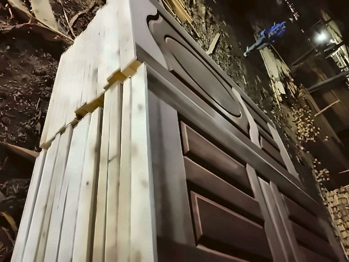 Dark panel doors stacked beside planed timber in the workshop